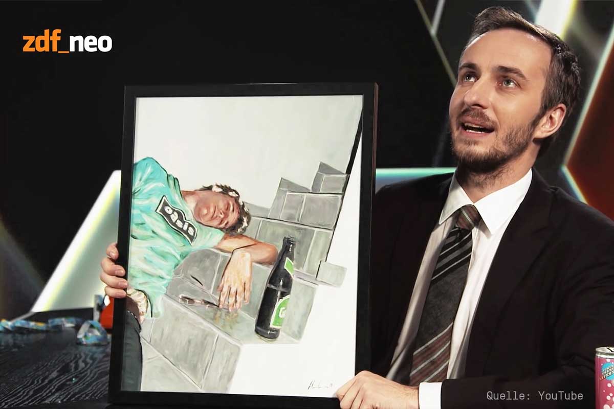 Screenshot von Jan Böhmermann, der ein gemaltes Bild von Andreas Wundersee bei PRISM IS A DANCER in die Kamera hält